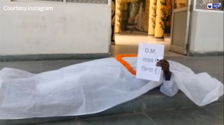 बस्ती में कागज़ों पर मृत घोषित रिटायर कर्मचारी खुद को जिंदा साबित करने कफ़न ओढ़कर पहुंचा DM दफ्तर, देखें वीडियो!